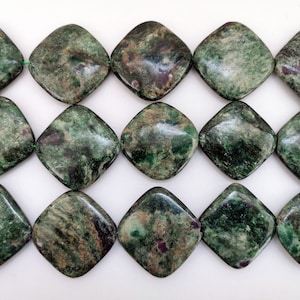 Può includere: Una collana di perline quadrate di pietra preziosa di colore verde e marrone. Le perline hanno un motivo maculato e sono di circa 2,5 cm di dimensione.