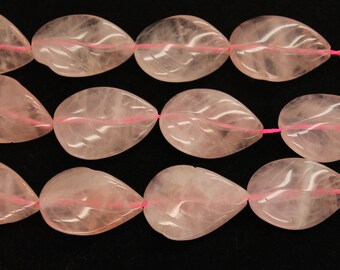 May include: A strand of pink rose quartz beads, each bead is carved in the shape of a leaf. The beads are strung on a pink elastic cord.