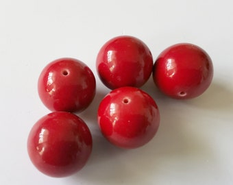 Könnte beinhalten: Sechs rote runde Perlen mit einem kleinen Loch in der Mitte jeder Perle.
