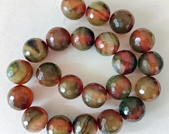 Könnte beinhalten: Eine Kette aus facettierten Achatperlen in Braun-, Orange- und Grüntönen. Die runden Perlen haben ein geometrisches Muster und eine polierte Oberfläche. Diese Perlen eignen sich für die Schmuckherstellung.