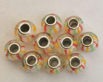Könnte beinhalten: Zehn weiße Glasperlen mit einem silbernen Metallring. Die Perlen sind mit roten, gelben und grünen Streifen verziert.