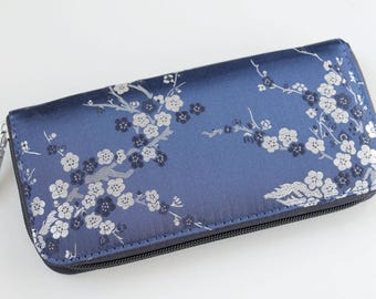 Könnte beinhalten: Eine blaue Reißverschlusstasche mit einem weißen Blumenmuster. Die Tasche ist aus einem weichen, seidenartigen Stoff.