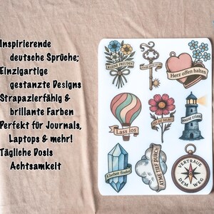 May include: A sheet of stickers with various designs, including a hot air balloon, a lighthouse, a compass, and floral elements. The stickers have German text and are accompanied by two paintbrushes.