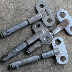 May include: Four antique silver-toned keys with a T-shaped handle. The keys have a worn, aged look and are slightly rusted.