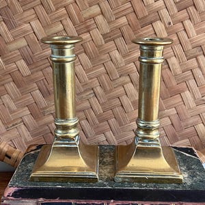 May include: A white ceramic mug with a black handle and the text "But First, Coffee" in a black, bold font. The mug is on a white surface.