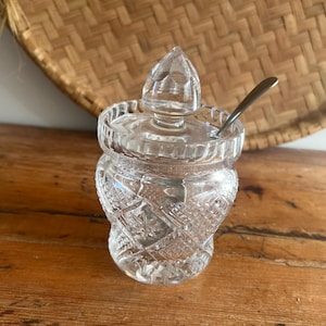 Peut inclure: Un sucrier en verre transparent orné d'un motif taillé en diamant et en étoile sur l'extérieur. Le récipient comprend un couvercle amovible assorti avec une prise en forme de pointe et une petite cuillère en métal argenté à l'intérieur.