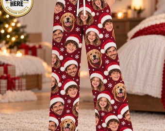 May include: Maroon pajama pants featuring a repeating pattern of human faces and golden retriever dog faces, each wearing a red and white Santa hat. The pants have a white drawstring at the waist and are decorated with small white snowflake icons.