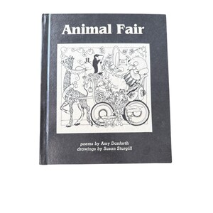 Könnte beinhalten: Ein Hardcover-Buch mit dem Titel "Animal Fair" mit schwarzem Einband. Das Cover zeigt eine Schwarz-Weiß-Illustration von Tieren in einer Parade. Der Text des Buches enthält die Namen des Autors und des Illustrators.