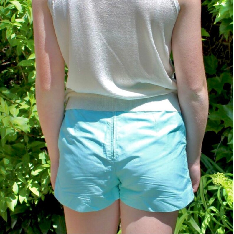 May include: A light blue pair of shorts with a white tank top. The shorts have a high waist and a relaxed fit.
