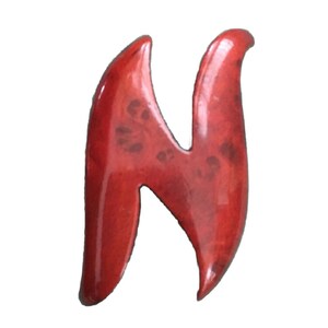 May include: A red ceramic letter N with a glossy finish. The letter is stylized with a unique, flowing design.