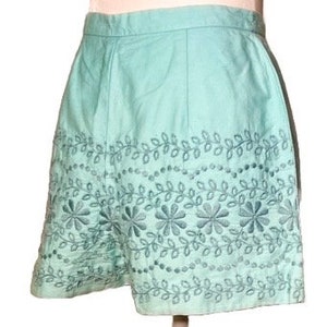 May include: A light blue pair of shorts with an embroidered floral design around the hem.