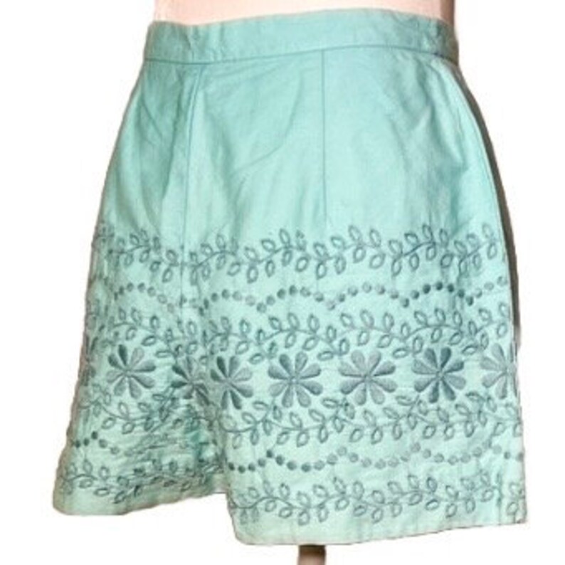 May include: A light blue pair of shorts with an embroidered floral design around the hem.