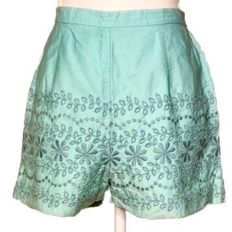 May include: Mint green shorts with embroidered floral details around the hem.