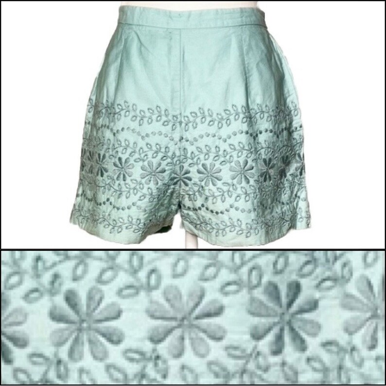 May include: Light blue shorts with a floral embroidery design. The embroidery features small flowers and leaves in a repeating pattern.
