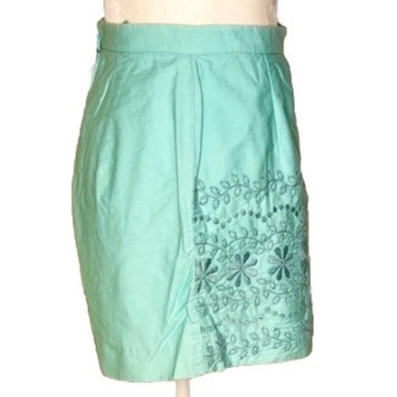 May include: A light blue skirt with embroidered floral details along the bottom hem.