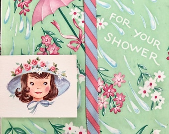 May include: A green and white card with a pink umbrella and flowers. The card says "For Your Shower".