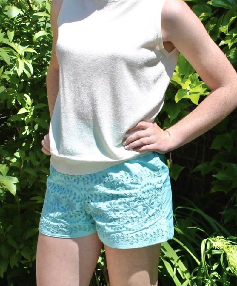 May include: A pair of light blue embroidered shorts with a floral pattern. The shorts are made of a lightweight fabric and have a relaxed fit.