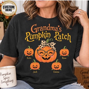 May include: A black t-shirt featuring the text Grandma's Pumpkin Patch in orange and yellow. The design includes a large central pumpkin wearing leopard print glasses and a matching bow, surrounded by four smaller pumpkins labeled Kate, Rose, Jack, and Emma.