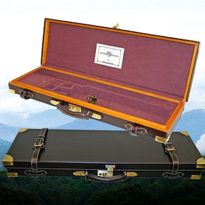 May include: Two leather gun cases. One is open, revealing a burgundy interior and wooden frame. The other is closed, with brass hardware and leather straps. Both cases are brown and black, with a classic design.