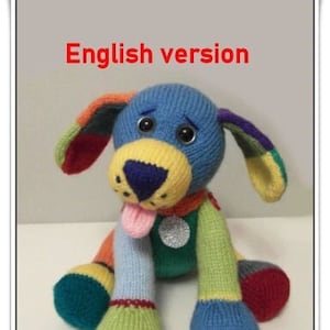 May include: A colorful knitted dog toy with a blue body, yellow nose, and multi-colored ears and legs. The toy has a pink tongue sticking out and a silver charm on its neck. The text "English version" is written in red at the top of the image. The text "Phoenixknits ©" is written at the bottom of the image.