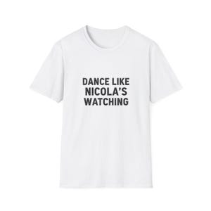 May include: A white t-shirt with a crew neck and short sleeves. The front features the black text "DANCE LIKE NICOLA'S WATCHING". A simple, casual design suitable for everyday wear.