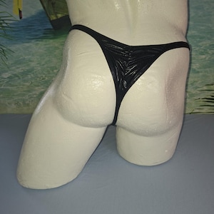 May include: A white ceramic mug with a black handle and the text "But First, Coffee" in a black, handwritten-style font. The mug is on a white surface.