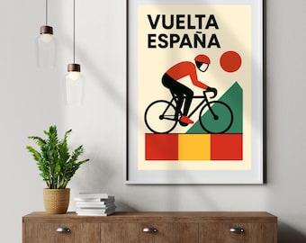Op de afbeelding: Een ingelijste poster met de tekst "VUELTA ESPAÑA" en een illustratie van een wielrenner. De wielrenner is afgebeeld in rood en zwart, op een zwarte fiets. De achtergrond toont een rode zon, een groene berg en rode, gele en groene blokken.