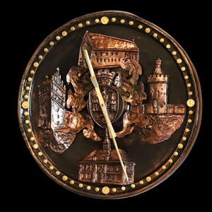 Könnte beinhalten: Eine runde Wanduhr aus Kupfer mit schwarzem Hintergrund und goldenen Akzenten. Das Zifferblatt der Uhr zeigt ein 3D-Design eines Schlosses mit einem Wappen und einem Turm.