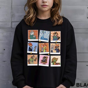 May include: Black sweatshirt featuring a grid of cartoon character images in a polaroid style. The images include various anthropomorphic animals. The word "BLACK" is printed in white at the bottom right corner.