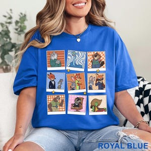 Pode incluir: Camiseta azul royal com uma grade de retratos de personagens de desenhos animados de animais em molduras estilo Polaroid. Os retratos mostram v&aacute;rios animais em diferentes roupas e poses. A camiseta tem gola redonda e mangas curtas.