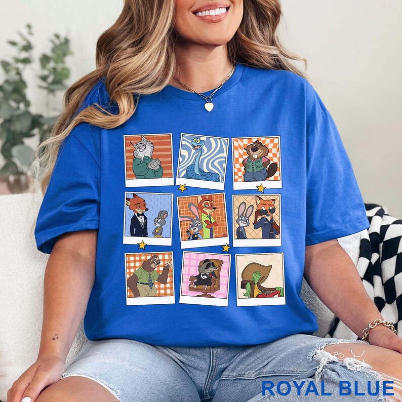 Pode incluir: Camiseta azul royal com uma grade de retratos de personagens de desenhos animados de animais em molduras estilo Polaroid. Os retratos mostram v&aacute;rios animais em diferentes roupas e poses. A camiseta tem gola redonda e mangas curtas.