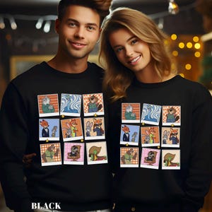 May include: Black sweatshirt featuring a grid of cartoon character images in a retro photo style. The sweatshirt has a crew neck and long sleeves. The word "BLACK" is printed at the bottom of the sweatshirt.