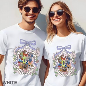 May include: White t-shirts featuring a cartoon design with various animal characters inside an oval frame. The frame is decorated with a light purple bow, flowers, and pearls. The word "WHITE" is printed at the bottom.