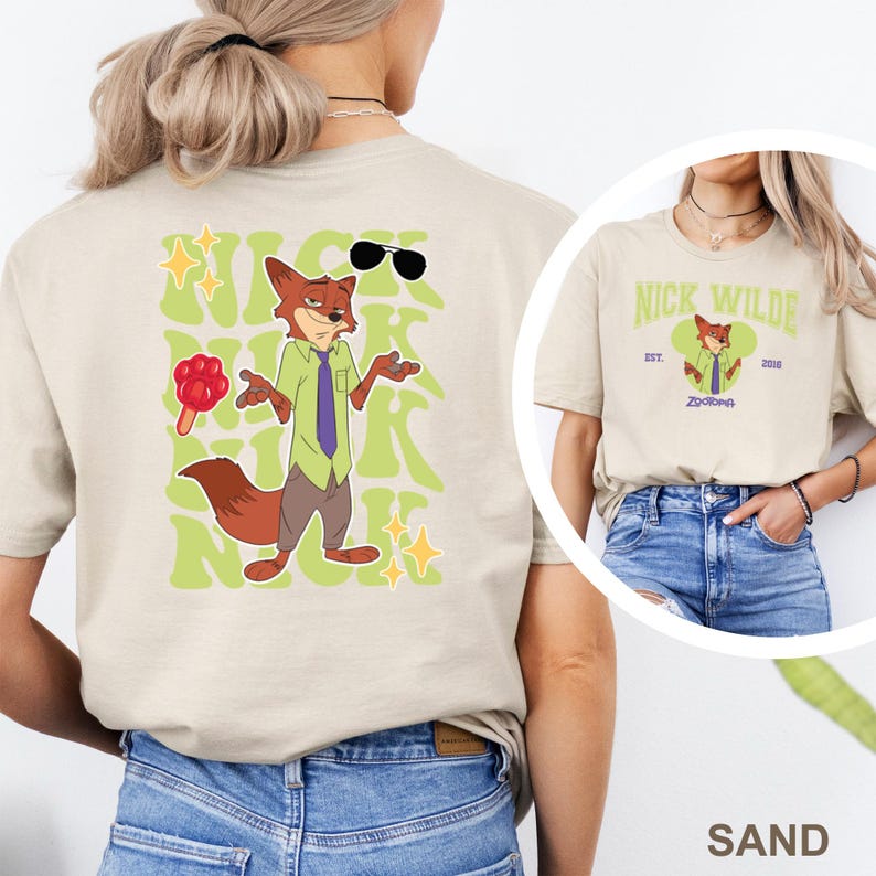 K&ouml;nnte beinhalten: Sandfarbenes T-Shirt mit einem Cartoon-Fuchs-Charakter mit Sonnenbrille und Lutscher. Das Design auf der R&uuml;ckseite enth&auml;lt den Namen "Nick" in einer stilisierten Schriftart. Ein kleineres Bild des Charakters befindet sich auf der Vorderseite mit dem Text "Nick Wilde" und "Zootopia".