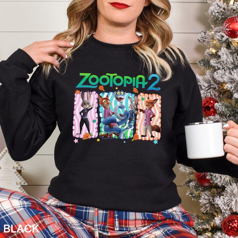 May include: Black crewneck sweatshirt featuring the text "Zootopia 2" in green and blue. The graphic includes cartoon characters in colorful frames. The word "BLACK" is printed at the bottom.