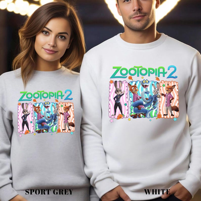 May include: Two sweatshirts, one sport grey and one white, each featuring the text "ZOOTOPIA 2" in green and blue. The design includes cartoon characters in colorful frames. The sport grey sweatshirt is labeled "SPORT GREY" and the white one is labeled "WHITE".