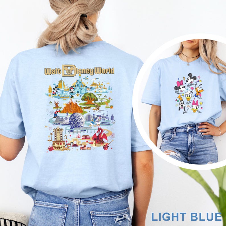 Op de afbeelding: Lichtblauw T-shirt met een kleurrijke afbeelding van Disney-personages en een kaart van Walt Disney World. Het shirt heeft korte mouwen en een ronde hals. De tekst "Walt Disney World" staat op de achterkant.