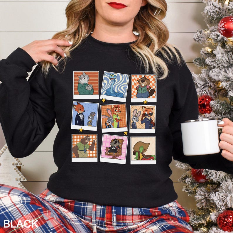 May include: Black crewneck sweatshirt featuring a collage of cartoon character images in polaroid-style frames. The word "BLACK" is printed in white at the bottom. The sweatshirt is worn by a person.