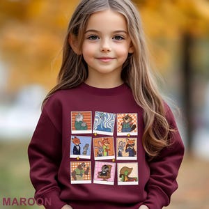 May include: A maroon sweatshirt featuring a grid of cartoon character images. The images are in a polaroid style, with a variety of animal characters in different poses. The word "MAROON" is printed at the bottom of the sweatshirt.