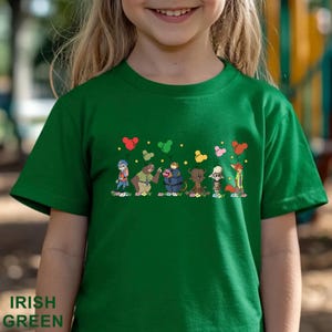 Puede incluir: Camiseta verde irland&eacute;s con un dise&ntilde;o de dibujos animados de personajes de animales sosteniendo globos. La camiseta tiene las palabras "Irish Green" impresas en la parte inferior. El dise&ntilde;o incluye un conejo, un oso y un zorro.
