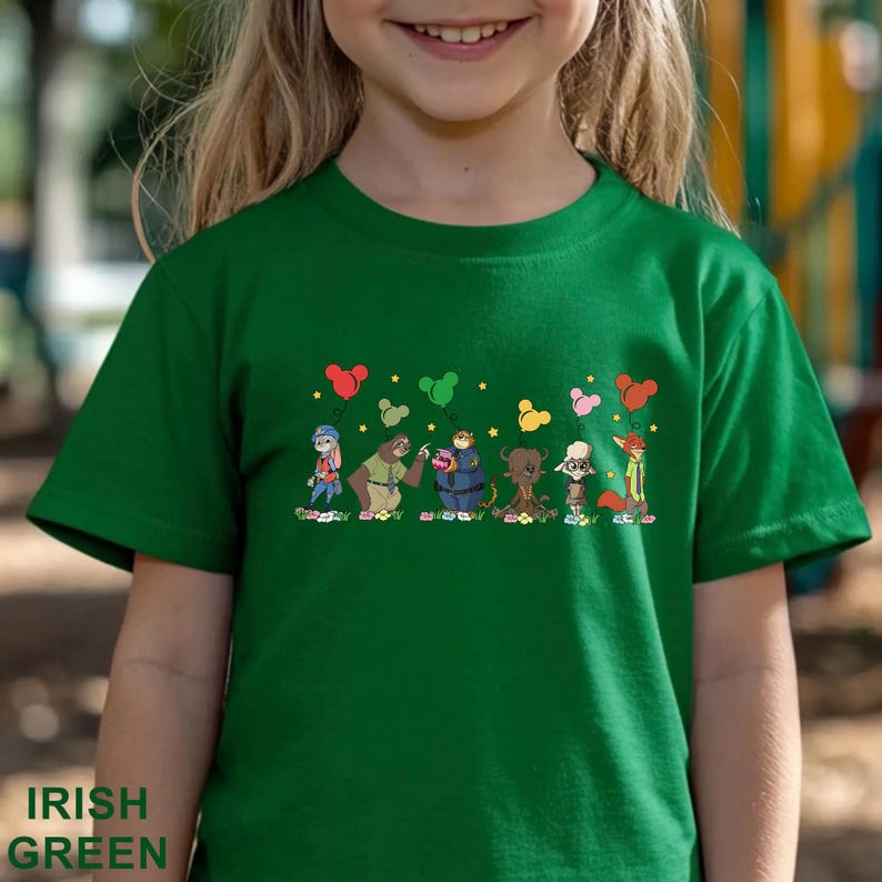 Puede incluir: Camiseta verde irland&eacute;s con un dise&ntilde;o de dibujos animados de personajes de animales sosteniendo globos. La camiseta tiene las palabras "Irish Green" impresas en la parte inferior. El dise&ntilde;o incluye un conejo, un oso y un zorro.