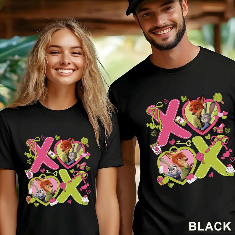 Puede incluir: Camisetas negras con un dise&ntilde;o gr&aacute;fico colorido con los personajes Nick Wilde y Judy Hopps de Zootopia. El dise&ntilde;o incluye elementos rosas y verdes, corazones y las letras X y O. La palabra "BLACK" est&aacute; impresa en la parte inferior derecha.