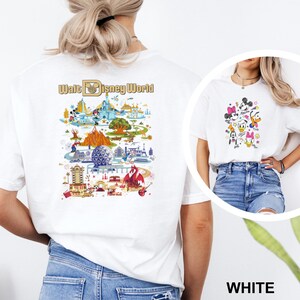 Op de afbeelding: Witte T-shirts met kleurrijke afbeeldingen. E&eacute;n shirt heeft een gedetailleerde kaart van Walt Disney World met de tekst "Walt Disney World". Het andere shirt toont stripfiguren, waaronder Mickey en Minnie Mouse.
