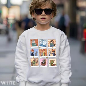 May include: White sweatshirt featuring a grid of cartoon character images. The images are in a polaroid style with a star at the bottom. The sweatshirt is worn by a child wearing sunglasses.