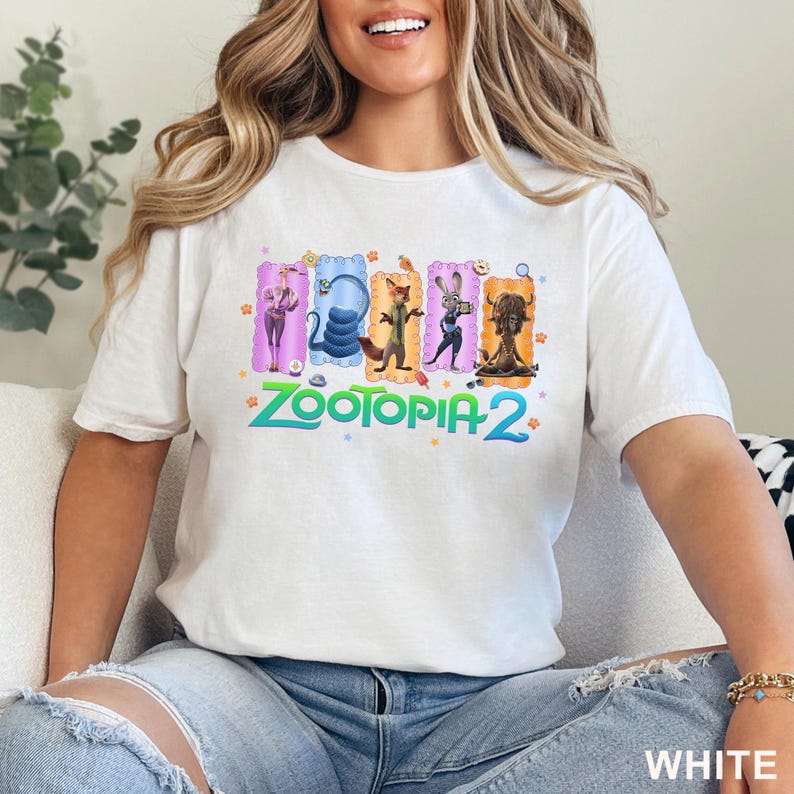 May include: White t-shirt featuring the text "Zootopia 2" in green and blue. The shirt has a colorful graphic of characters from the movie. The word "WHITE" is printed in white at the bottom right.