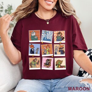 Pode incluir: Camiseta bord&ocirc; com uma grade de nove imagens de personagens de desenhos animados em estilo polaroid, cada uma com uma estrela. A palavra "MAROON" est&aacute; impressa no canto inferior direito. A camiseta &eacute; de cor vermelho escuro.