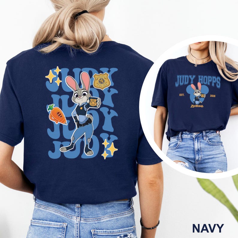 K&ouml;nnte beinhalten: Marineblaues T-Shirt mit Judy Hopps aus Zootopia. Auf der R&uuml;ckseite des Shirts ist ein Cartoon-Bild von Judy Hopps in Polizeiuniform mit dem Text "Judy" und "Zootopia" zu sehen. Auf der Vorderseite des Shirts steht "Judy Hopps" und "Zootopia".