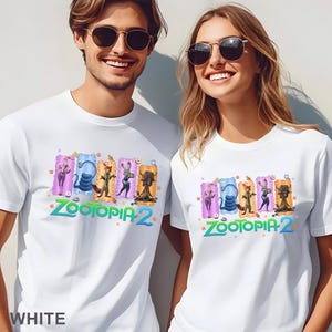 May include: White t-shirts featuring a colorful graphic of characters from Zootopia 2. The design includes Judy Hopps, Nick Wilde, and other characters. The text "Zootopia 2" is in green and blue. The word "WHITE" is at the bottom.