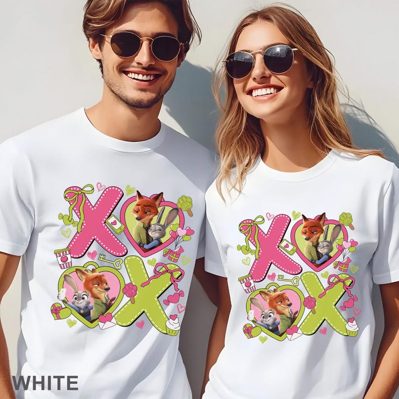 Puede incluir: Camisetas blancas con un dise&ntilde;o gr&aacute;fico colorido con el texto "XOX" e im&aacute;genes de un zorro y un conejo en un marco en forma de coraz&oacute;n. El dise&ntilde;o incluye rosa, verde y otros colores pastel. La palabra "WHITE" est&aacute; impresa en la parte inferior.