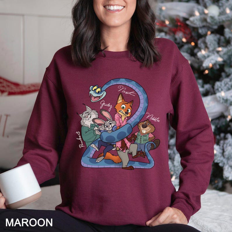 May include: Maroon sweatshirt featuring a cartoon graphic of characters from a movie. The graphic includes a blue snake with the number 2, and the names "Judy", "Nick", and "Nibbles". The word "MAROON" is printed at the bottom.